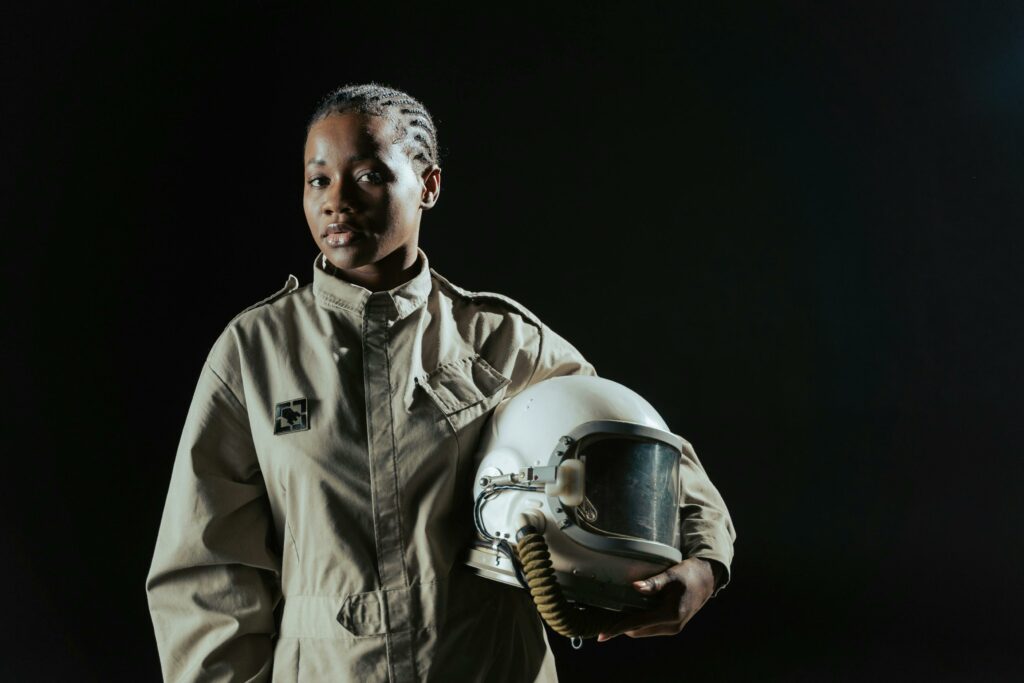 pexels-photo-7166814-7166814 Octopoda Solutions - A confident female astronaut in a spacesuit holding her helmet against a dark background.